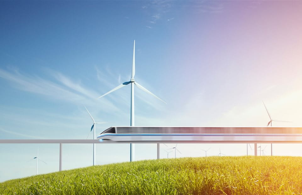 A moving train over a green meadow and wind turbines 