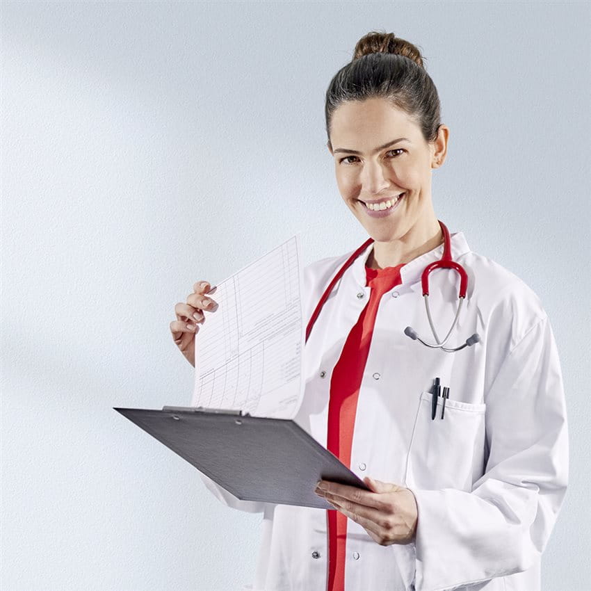 A doctor studies her notes and looks at the camera smiling