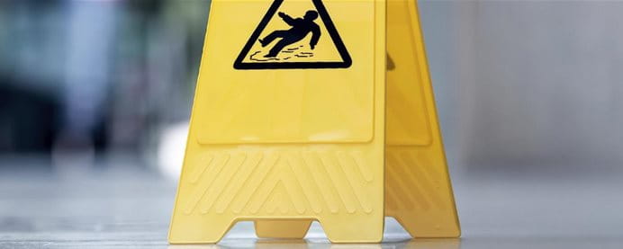 Un panneau indicateur de danger de glissade est posé sur le sol.