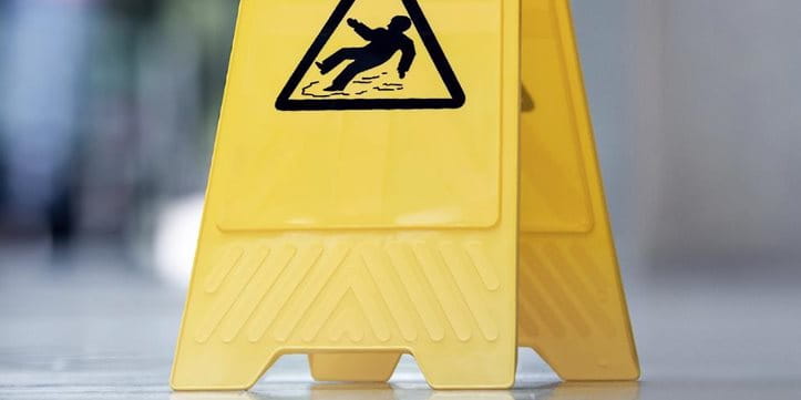 Un panneau indicateur de danger de glissade est posé sur le sol.