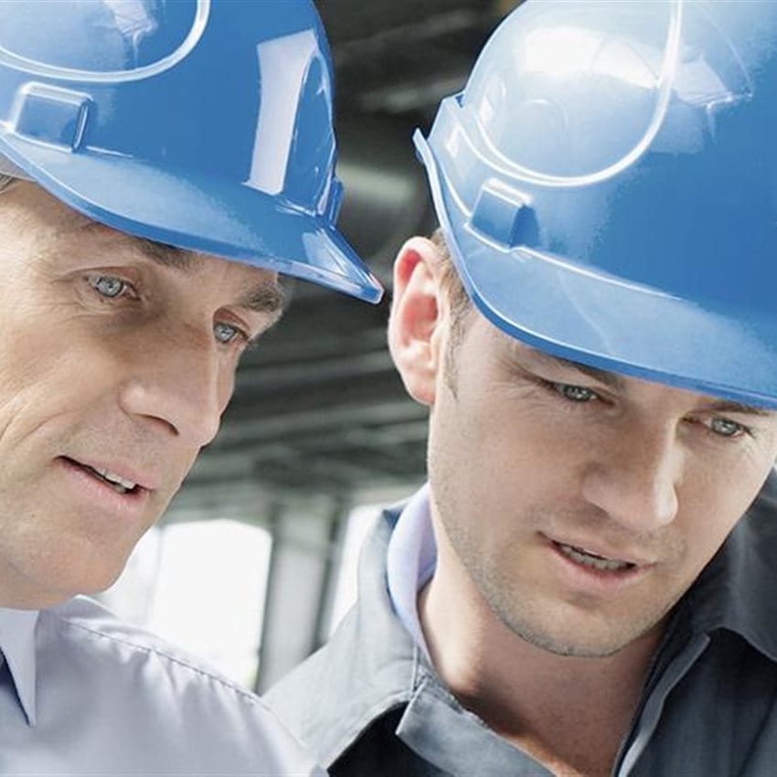 Deux hommes avec des casques de protection discutent sur un chantier.