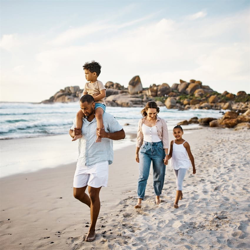 Coppia di famiglie a passeggio sulla spiaggia di sabbia con 2 bambini