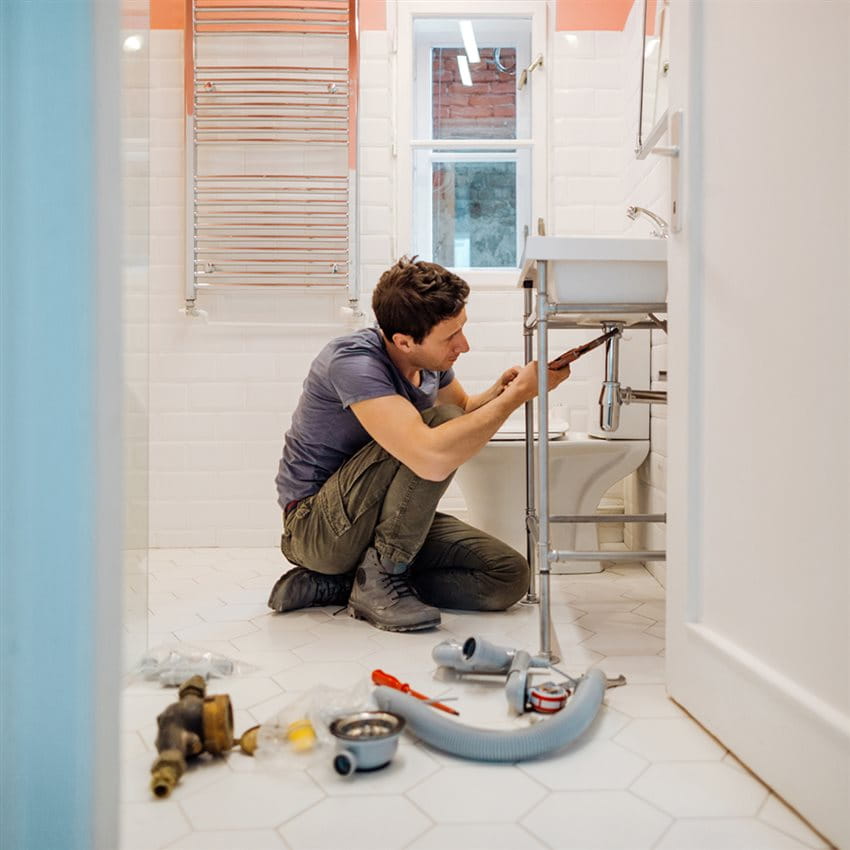 Artisan plombier dans la salle de bain en train de réparer le siphon