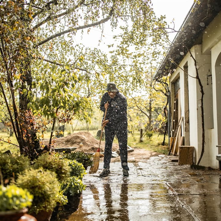Mann wischt nasse Terasse nach Dauerregen