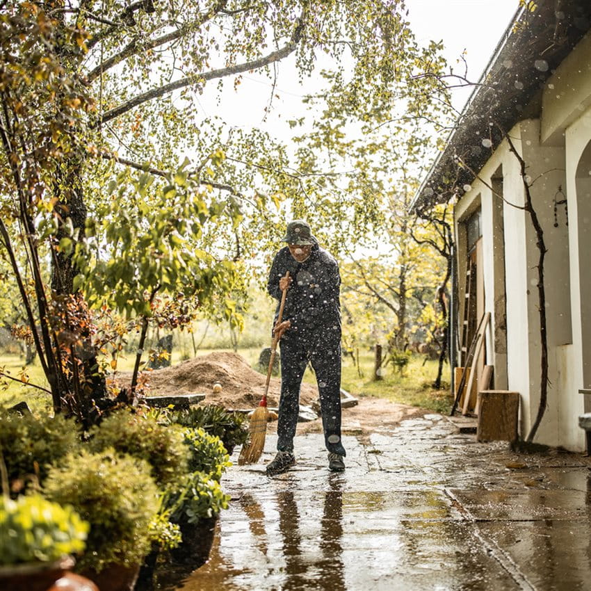 Mann wischt nasse Terasse nach Dauerregen