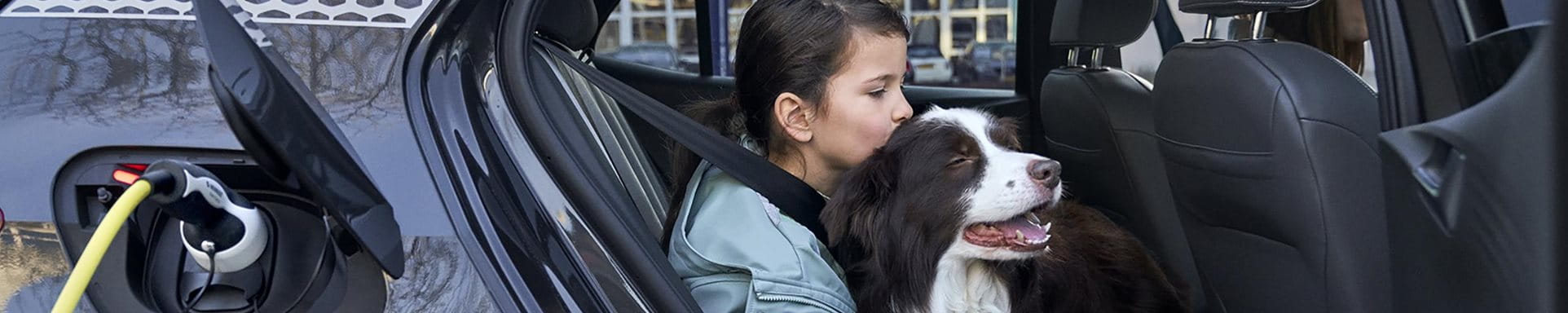 Maedchen kuschelt einen Hund im Auto