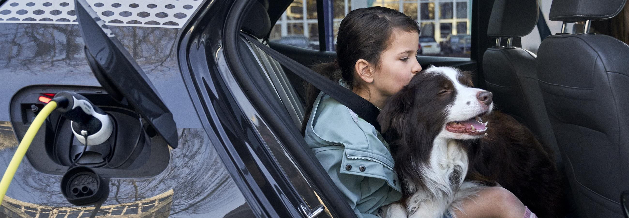 Girl cuddles a dog in the car