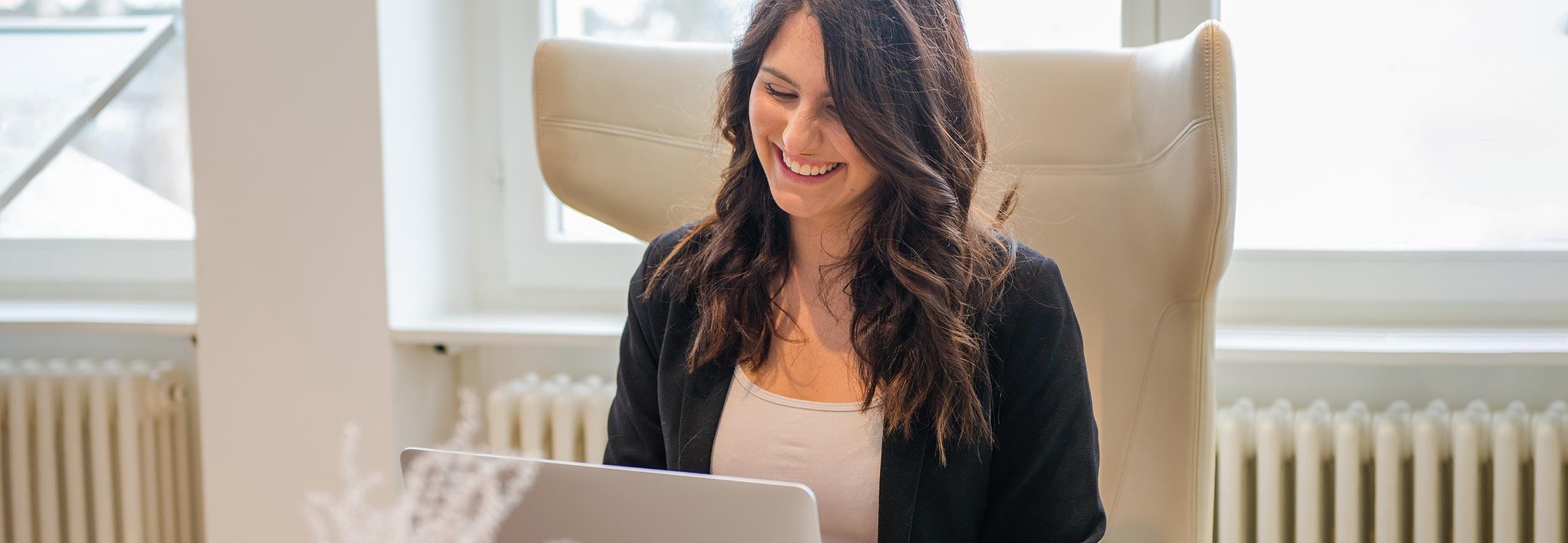 Jeune femme assise devant un ordinateur portable et riant
