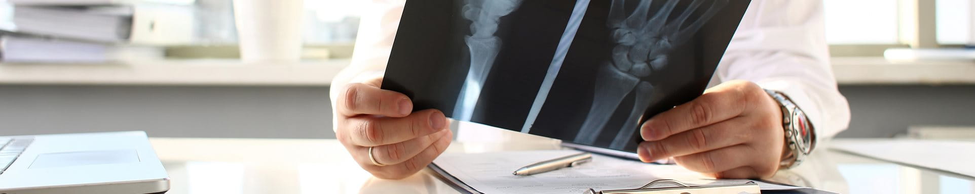 Un médecin s'assied à la table et regarde une image radiographique.