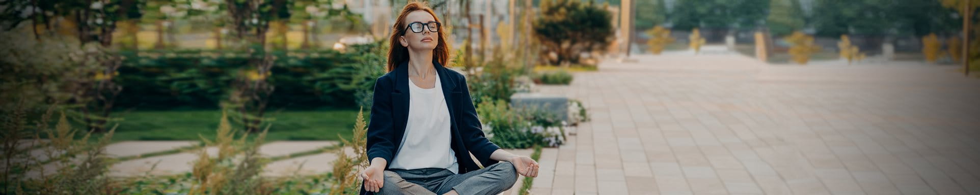  Frau sitzt im Park und macht Yoga