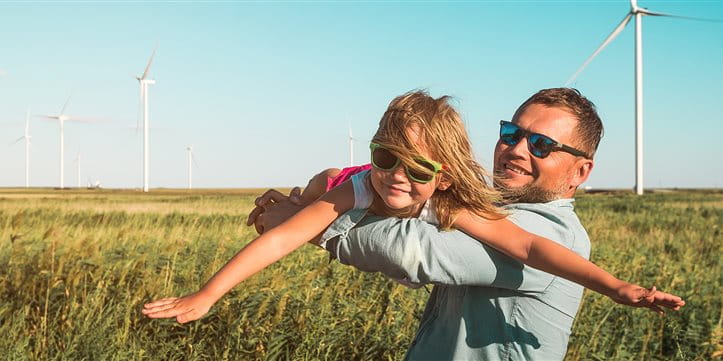 Uomo con bambino su un campo davanti a pale eoliche