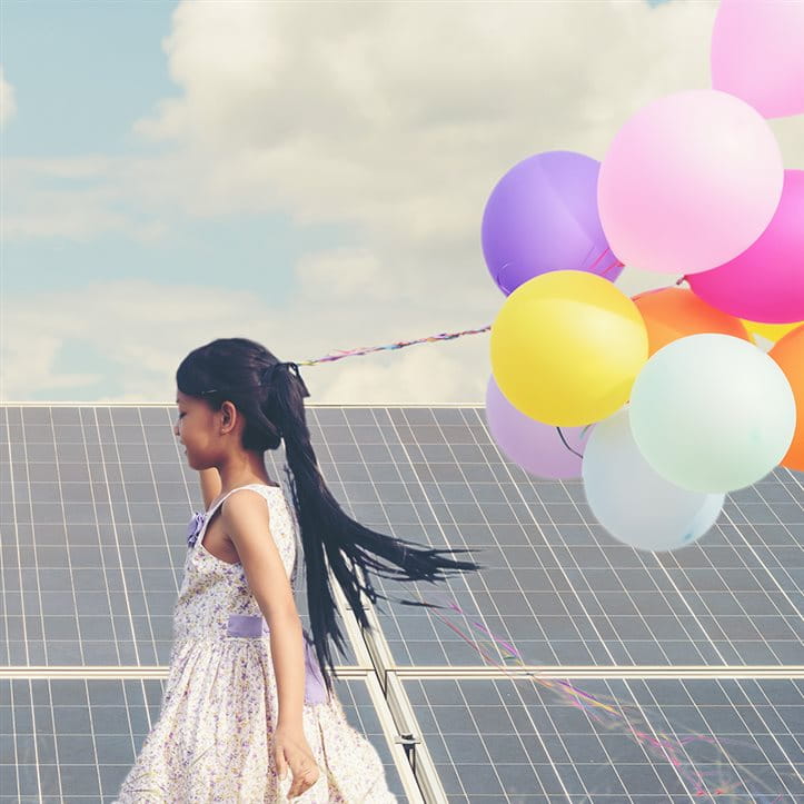 Child with balloons in front of solar panels