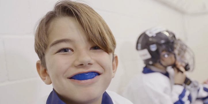 A young ice hockey player wearing a blue mouthguard