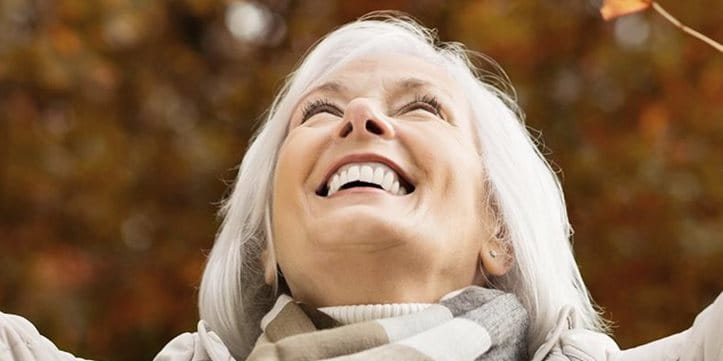 Una donna butta sorridendo delle foglie secche in aria.