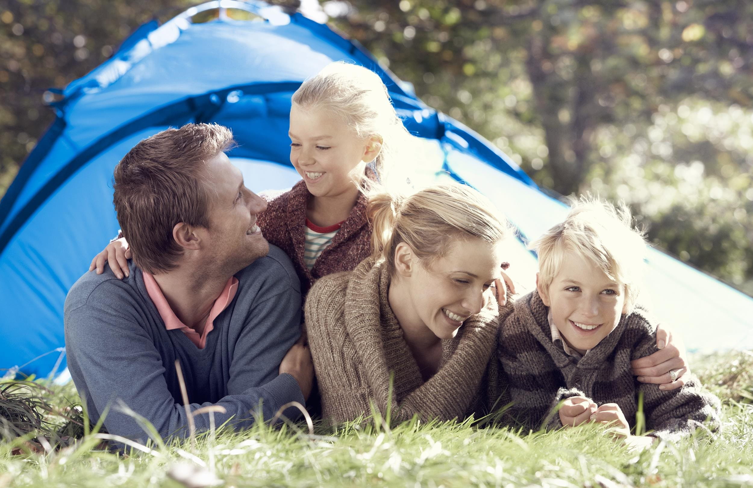 Famile liegt vor einem Zelt